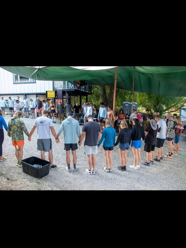 Large group of participants holding hands in a prayer circle before the race