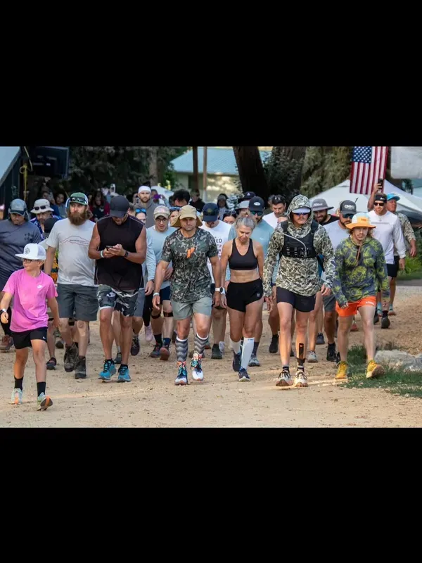 Pack of runners walking the trail together with an American flag in the background
