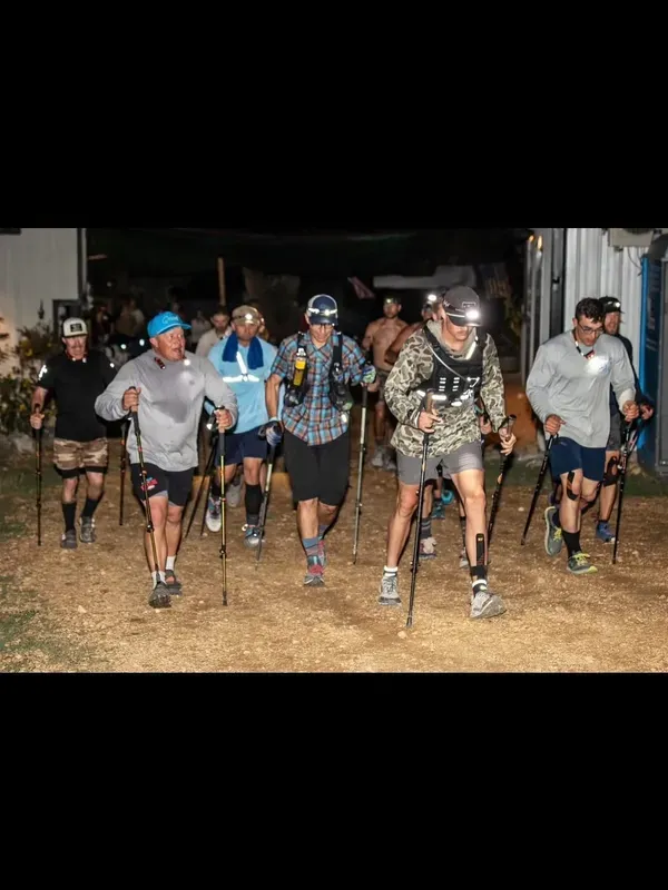 Runners with headlamps and trekking poles heading out for a night lap